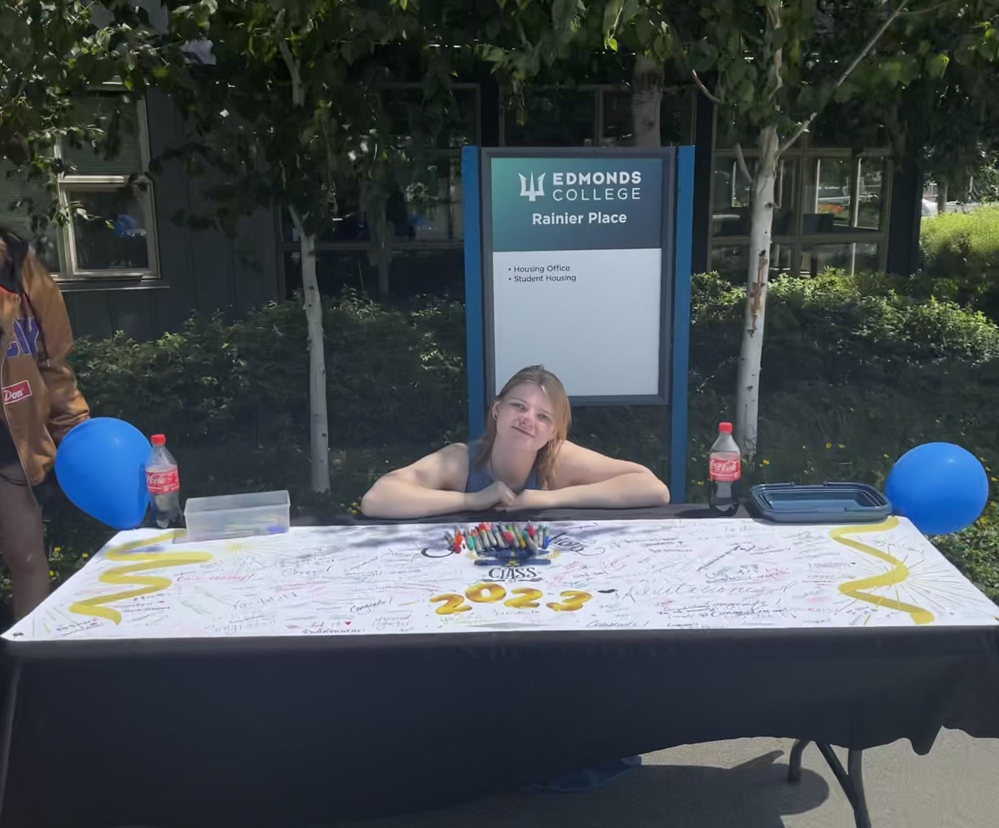 After collecting over 250 well wishes around Edmonds College, for the past 3 days, Adelaide Jaques takes a moment to pose next to the “Congratulations” banner. 