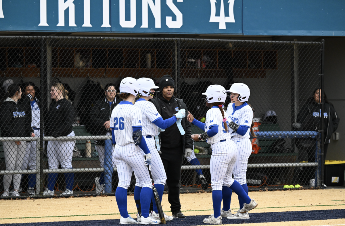 Triton softball players confer with coach Antionette Watson. The team is off to a strong start in 2026 with five wins and one loss so far.